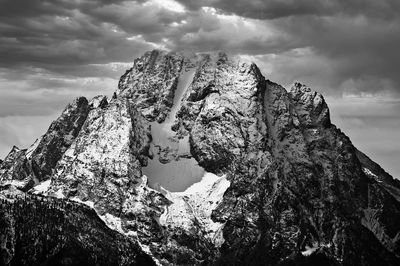 Black and white image of rugged mt. moran in grand teton national park breaking out of the clouds. 