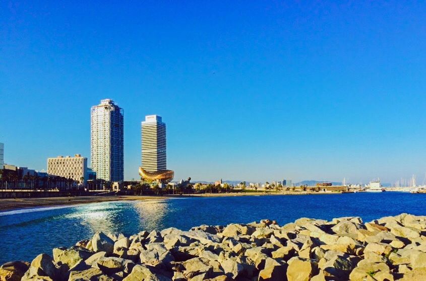 clear sky, water, blue, architecture, building exterior, built structure, city, copy space, cityscape, skyscraper, river, sea, tower, modern, urban skyline, outdoors, tall - high, day, sky, capital cities