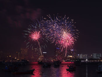 Firework display in city against sky at night