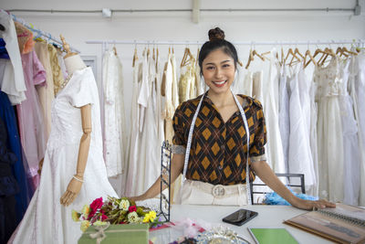 Portrait of smiling fashion designer standing at boutique