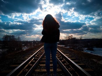 Rear view of woman standing on railroad tracks