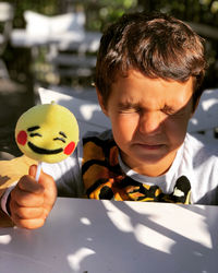 Cute boy holding toy sitting outdoors