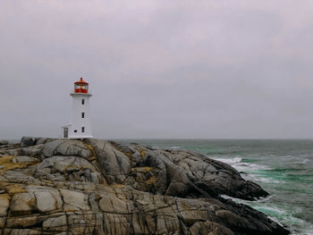 Lighthouse by sea against sky