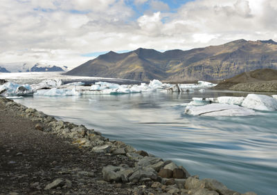 Scenic view of river by amidst against cloudy sky during winter