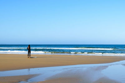 Man standing on beach against clear sky