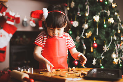 Girl preparing cookies on table during christmas