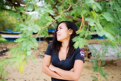 Young woman looking away while standing against plants