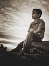 Portrait of boy sitting against sky
