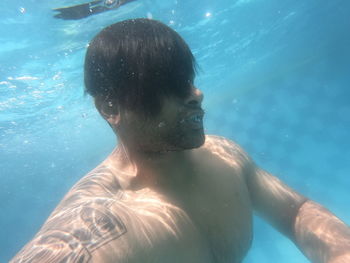 Portrait of shirtless man swimming in pool