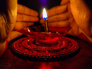 Close-up of hand holding lit candle