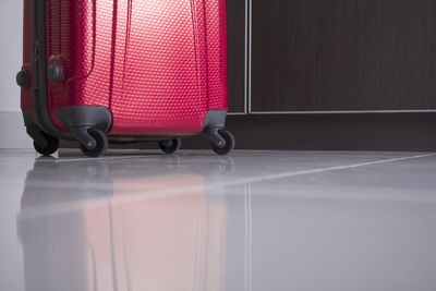 Surface level shot of red wheeled luggage on tiled floor