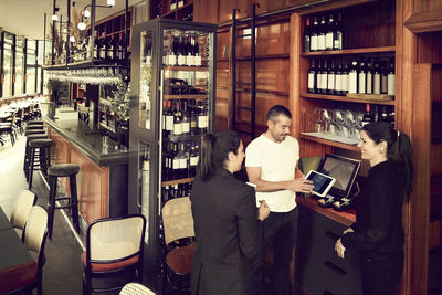 Smiling female owners talking with customer about order while standing in cafe