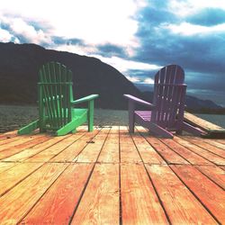 Pier on wooden boardwalk against cloudy sky