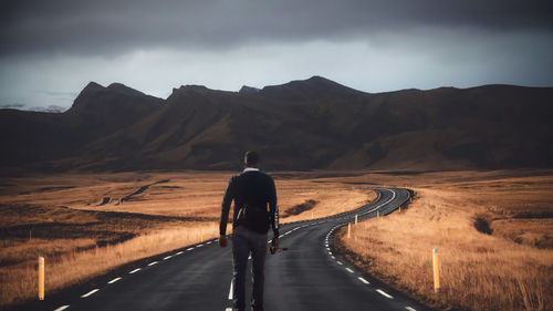 Rear view of man riding motorcycle on road