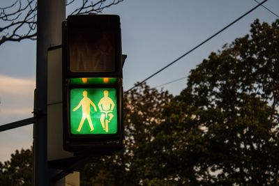 Illuminated road sign against blue sky