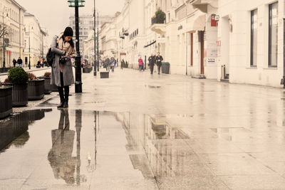 Rear view of woman walking on road by city