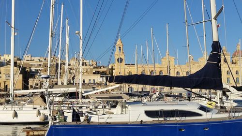 Sailboats moored on harbor against clear blue sky