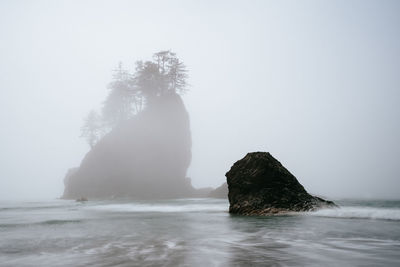 Rock formation in sea against clear sky