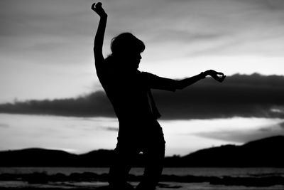 Silhouette woman standing by lake against sky during sunset