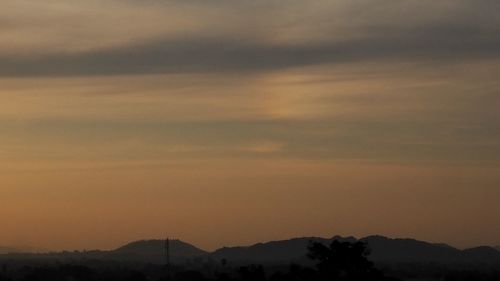 Scenic view of silhouette mountains against orange sky