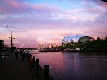 View of ferris wheel in city against cloudy sky