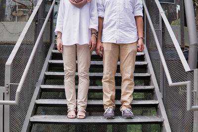 Low section of friends standing on railing