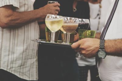 Midsection of waiter serving drinks to people