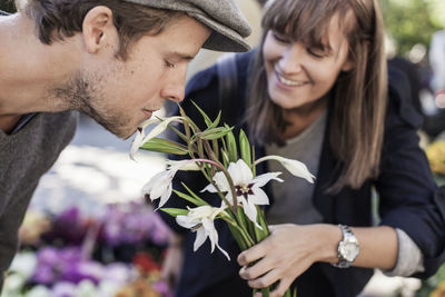 Young man smelling flowers held by woman in market