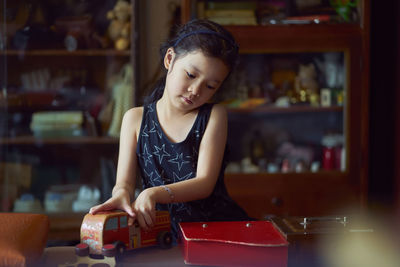 Girl playing toy on table while standing at home