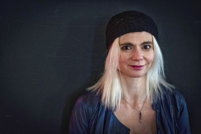 Portrait of smiling young woman against black background