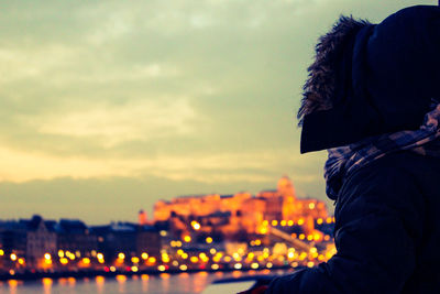 Man looking at cityscape against sky during sunset