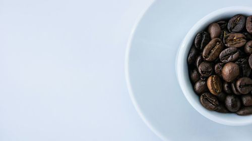 Directly above shot of coffee beans in cup against white background
