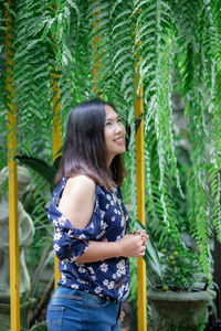 Young woman standing against plants