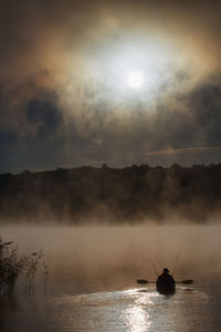 Silhouette boat in lake against sky