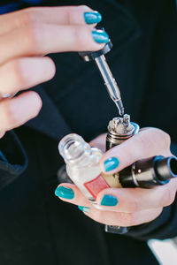 Midsection of woman holding electronic cigarette and dropper