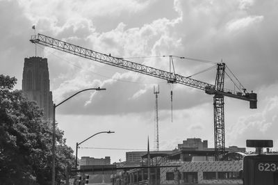 Low angle view of cranes against sky in city