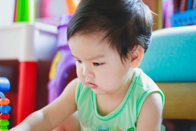 The cute asian boy toddler wearing the green vest are looking for his toy. portrait cute asian baby.