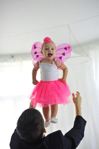 Rear view of father catching cheerful daughter at home