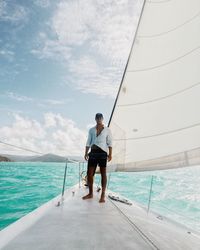 Man standing on boat sailing in sea against sky