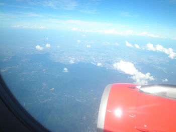 Cropped image of airplane flying over sea against blue sky