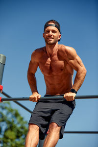 Portrait of young man exercising against sky