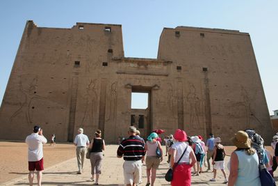 Tourists visiting temple of edfu against clear sky