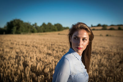 Portrait of young woman standing in wheat field