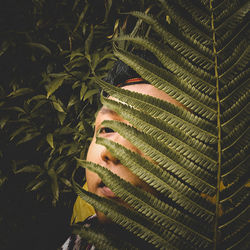 Young man hiding behind plants outdoors