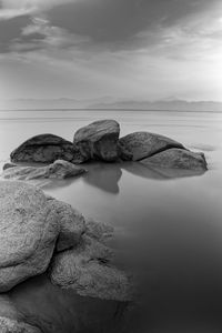 Rocks on shore by sea against sky