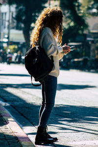 Full length of woman using phone on street