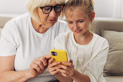 Portrait of young woman using phone while sitting on sofa at home