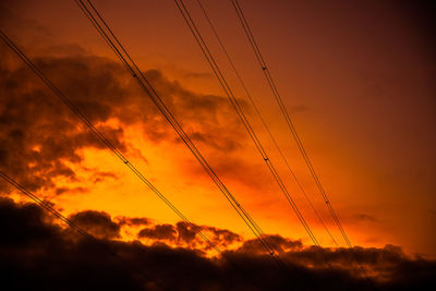 Low angle view of silhouette electricity pylon against romantic sky