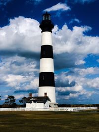 Low angle view of lighthouse by building against sky