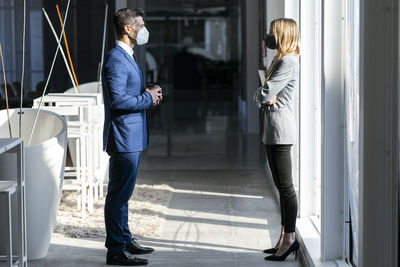 Business people wearing protective face mask standing at social distance while working in office during covid-19